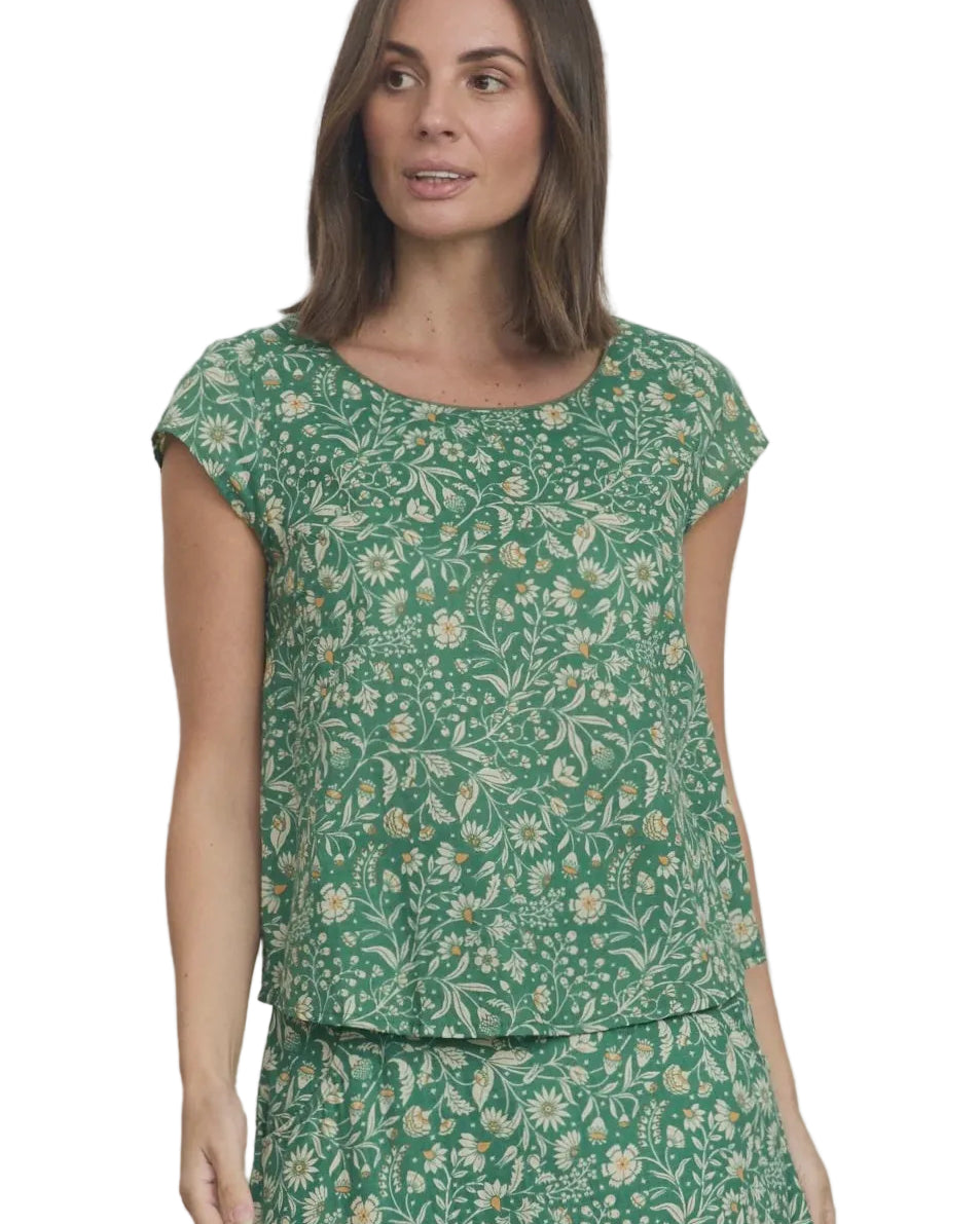 Woman wearing a green floral dress against a white wooden panel background
