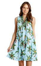 Woman wearing a light blue dress with tropical leaf pattern on a white background